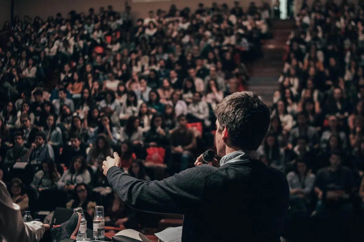 Clip three: a speaker with a handheld microphone addressing a warm-lit audience, cropped to a vertical frame